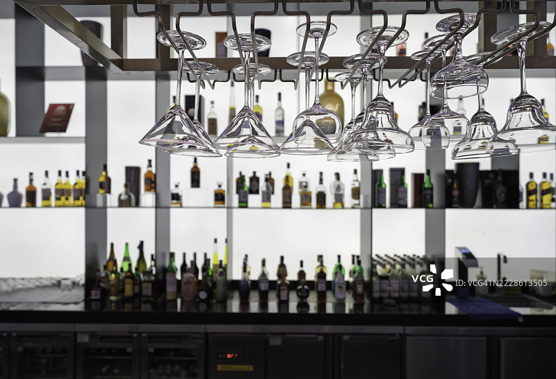 现代酒吧内部，悬挂的玻璃器皿和酒类展示图片素材
