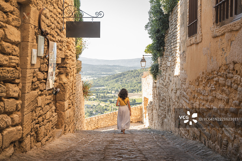 女人走在法国戈尔德斯的中世纪鹅卵石小巷中图片素材