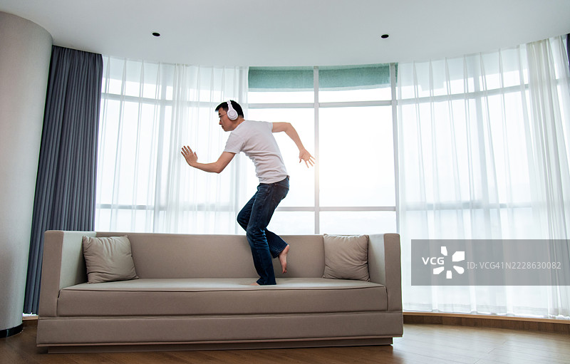男人戴着耳机在沙发上跳舞图片素材