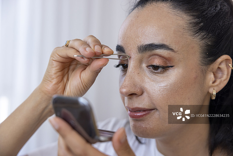 女人用镊子修整眉毛图片素材