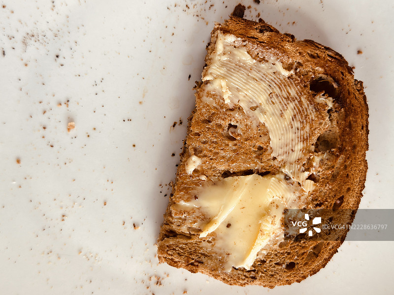 半片涂有黄油的烤粗粮面包特写图片素材