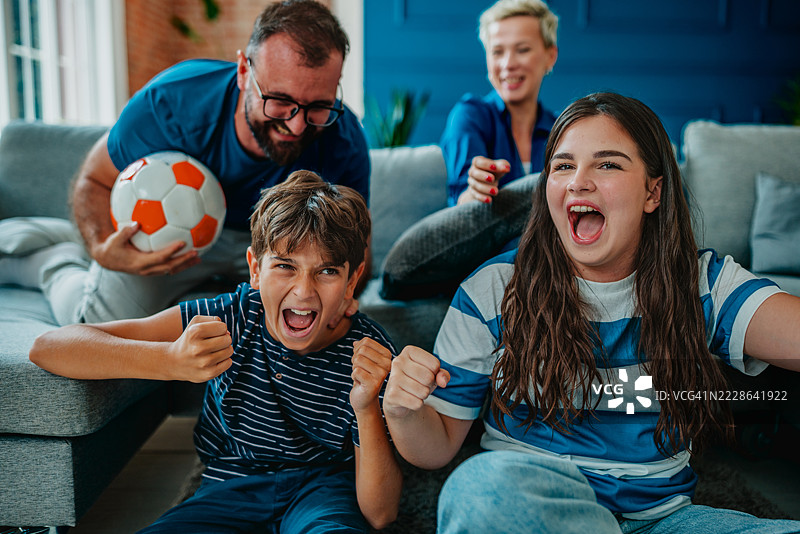 家庭在家中一起观看激动人心的足球比赛庆祝。图片素材