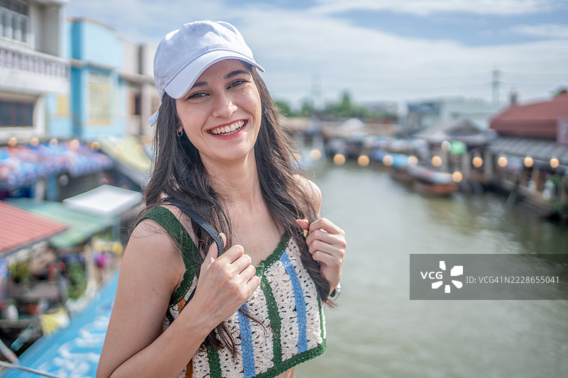 年轻女性游客在泰国的水上市场乘坐木船，品尝当地街头美食，享受东南亚之旅。图片素材