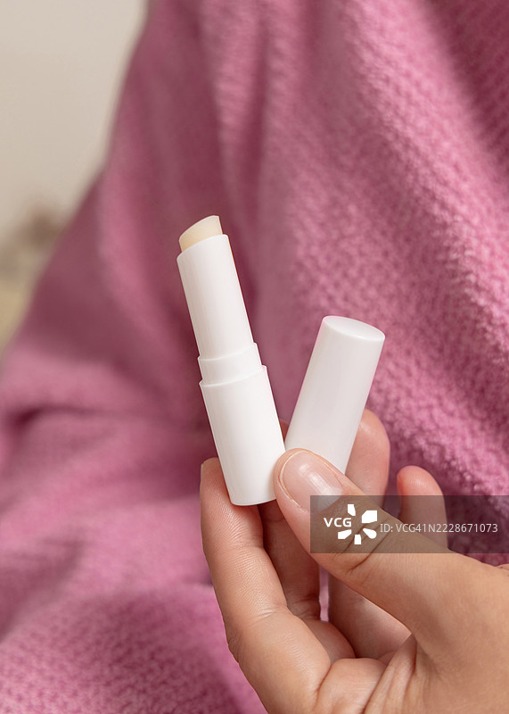 穿着粉色浴袍的女人手中拿着打开的润唇膏，特写，女孩风格的样板，布林迪西，普利亚，意大利图片素材