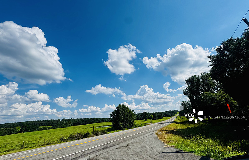 空旷的道路穿过树木，背景是天空，阿肯色州斯普林菲尔德，美国图片素材
