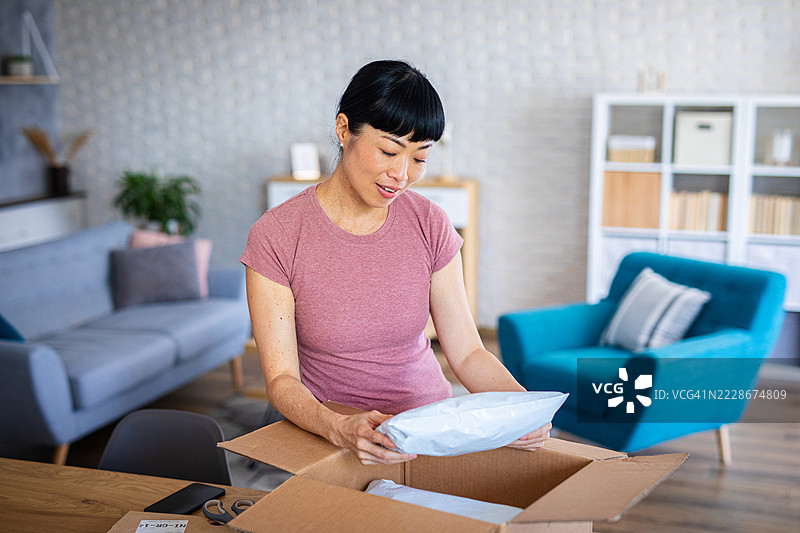 快乐的女性收到并打开她的在线快递图片素材