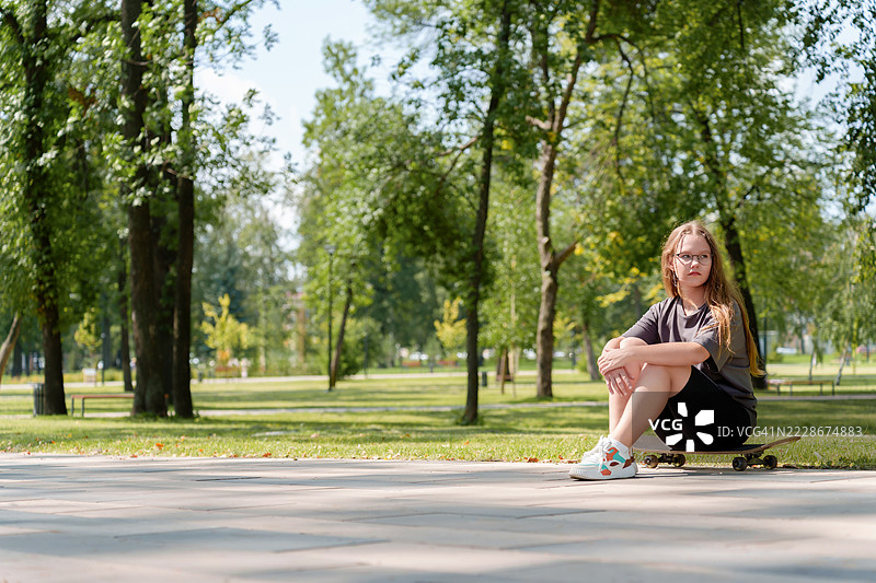 一位无忧无虑的少女穿着休闲夏装，悠闲地坐在上面。图片素材
