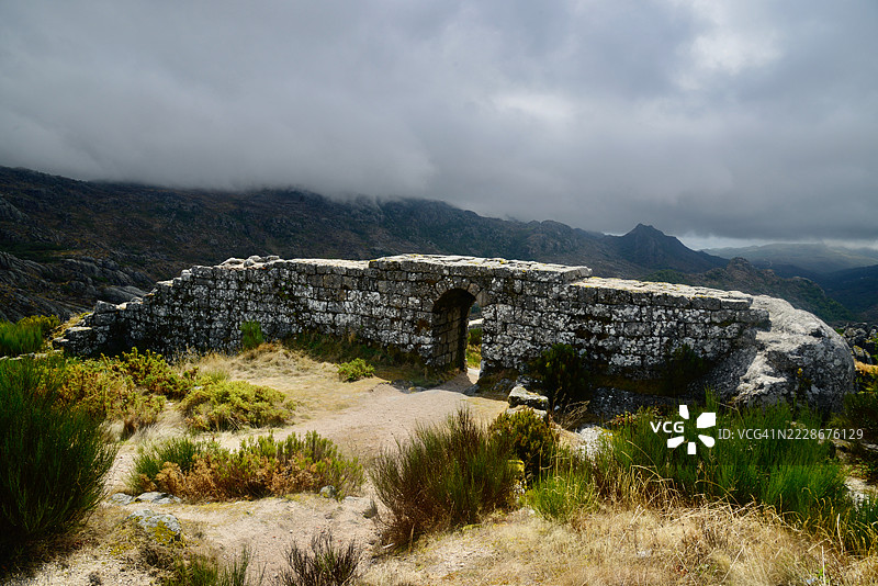 背对山脉的女性站在天空下，葡萄牙维亚纳堡图片素材