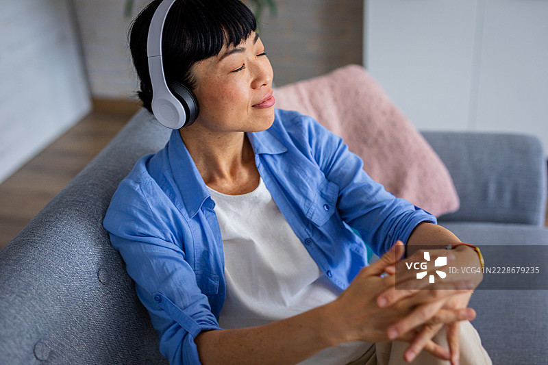 女人坐在沙发上放松，戴着耳机图片素材