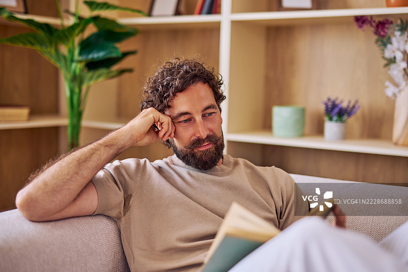 男人在家中沙发上放松地阅读一本书图片素材