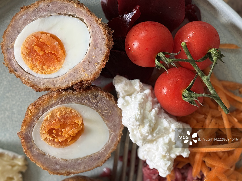 自制苏格兰蛋的图片，煮鸡蛋包裹在香肠肉中，外脆内嫩，搭配新鲜沙拉 / 健康的高蛋白餐。图片素材