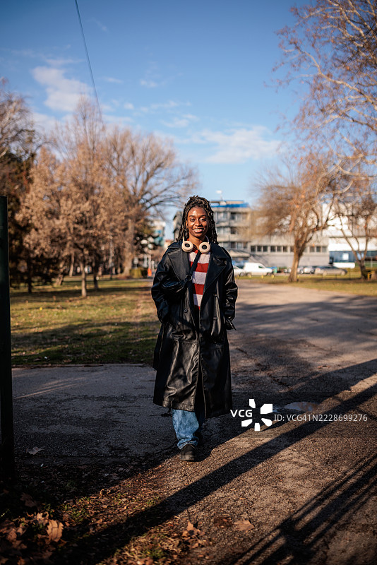 现代黑人女性穿着黑色外套在公共公园散步图片素材