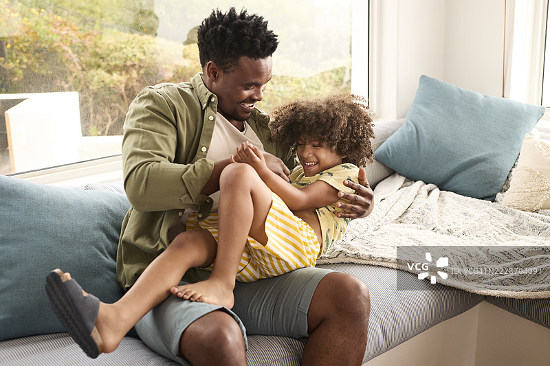 快乐的父亲在家里逗他的儿子笑图片素材