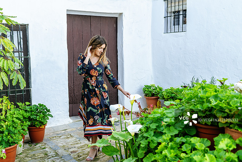 一位女士正在地中海村庄的白色街道上查看植物图片素材