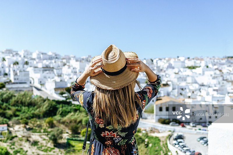 一位游客手持帽子，正在欣赏西班牙安达卢西亚的白色村庄维赫尔·德·拉·弗龙特拉。图片素材