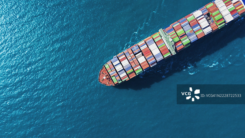 航拍视角的集装箱货船，满载集装箱，从商业港口的码头出发，适用于商业物流、进出口、运输或货运。图片素材