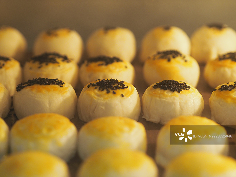 月饼，中华酥皮点心，咸蛋黄豆糕，泰式绿豆蛋糕，上面撒有黑芝麻，放在不锈钢格栅上图片素材