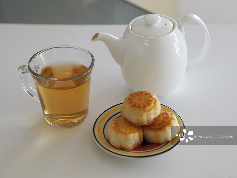 热茶甜点月饼，中华酥皮，咸蛋黄豆糕，泰式绿豆蛋糕，上面撒有黑芝麻，放在不锈钢格栅上。图片素材