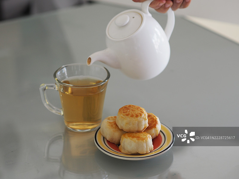 热茶甜点月饼，中华酥皮，咸蛋黄豆糕，泰式绿豆蛋糕，上面撒有黑芝麻，放在不锈钢格栅上。图片素材