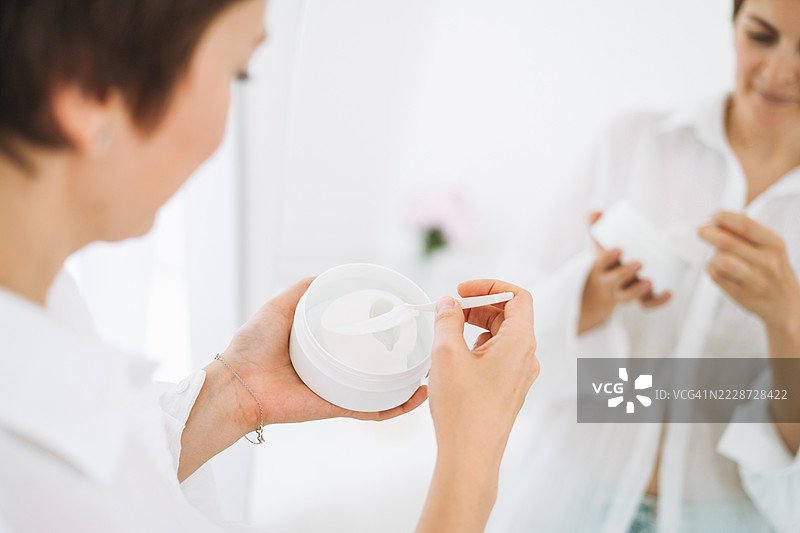 年轻女性在浴室中使用眼贴，进行护肤程序或家庭医疗护理图片素材