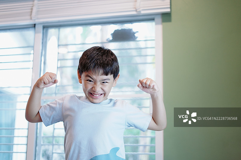 男孩举起双臂展示他的肌肉。图片素材