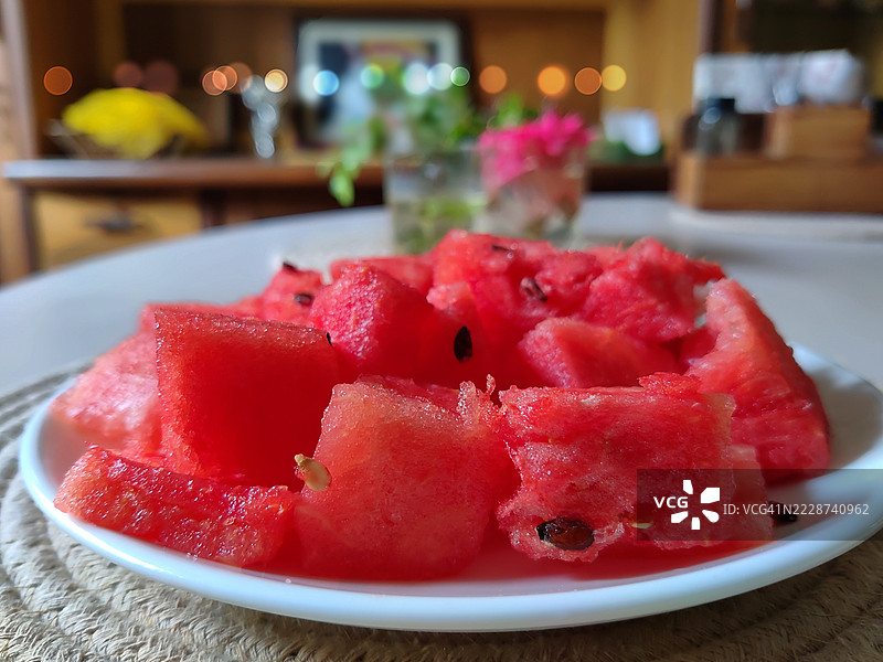 切好的新鲜西瓜特写，放在白色陶瓷盘子里，置于餐桌上的麻布垫上 / 静物摄影图片素材