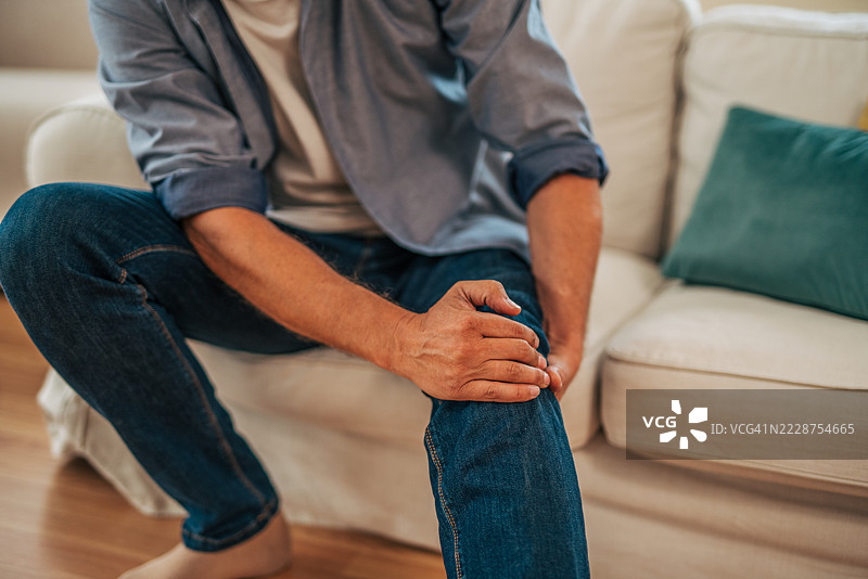 成熟男性在家中感受到膝盖疼痛图片素材