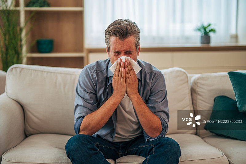 生病的中年男子在家里擤鼻涕图片素材