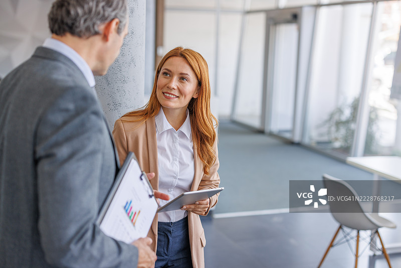 女商人手持平板电脑与男性同事在办公室讨论图表图片素材