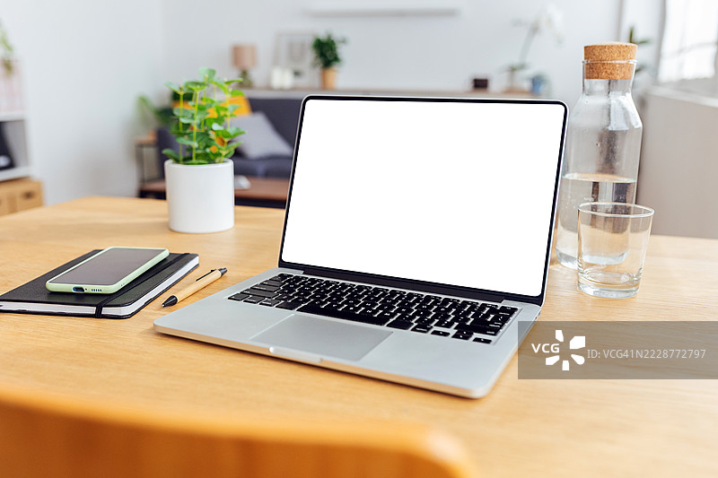 家用办公室布置中的木桌上放着一台黑屏的笔记本电脑图片素材