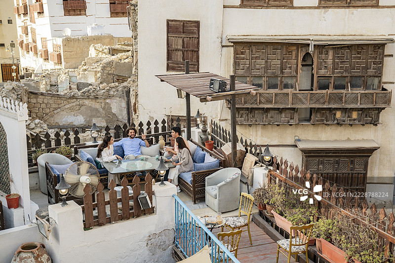 朋友们坐在吉达阿尔巴拉德的一家屋顶餐厅的桌子旁图片素材