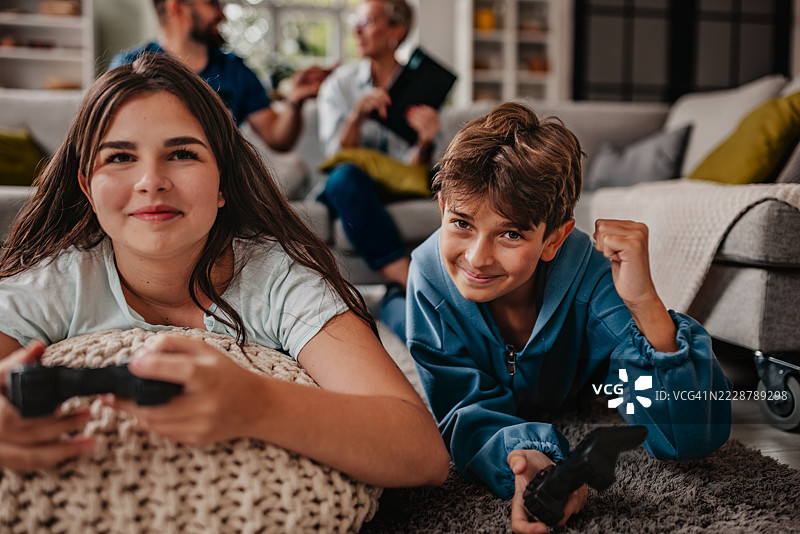 家庭在舒适的客厅里享受愉快的下午，一起玩视频游戏，分享欢声笑语。图片素材