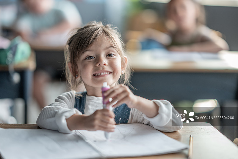 微笑的年轻女孩在教室活动中享受多彩的文具图片素材