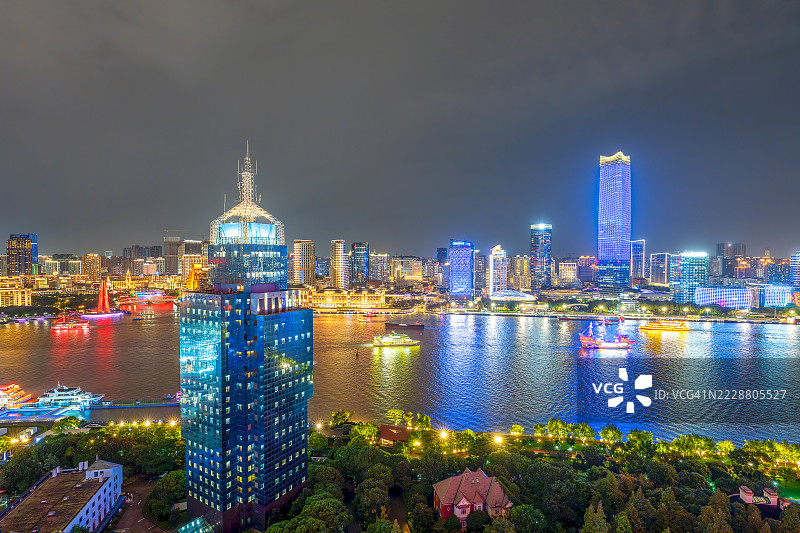 令人惊叹的鸟瞰图，展示了灯火辉煌的上海天际线和黄浦江上五彩斑斓的船只，展现了这座城市充满活力的夜景。图片素材