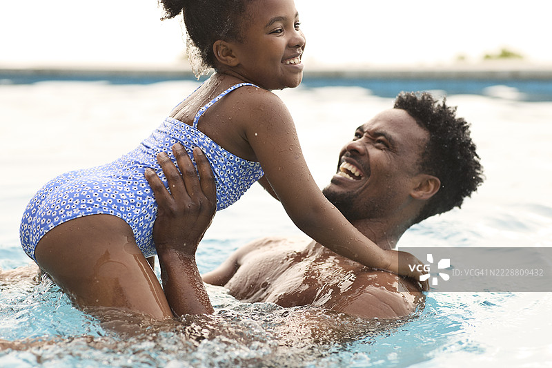 快乐的父亲和女儿在游泳池中畅游图片素材