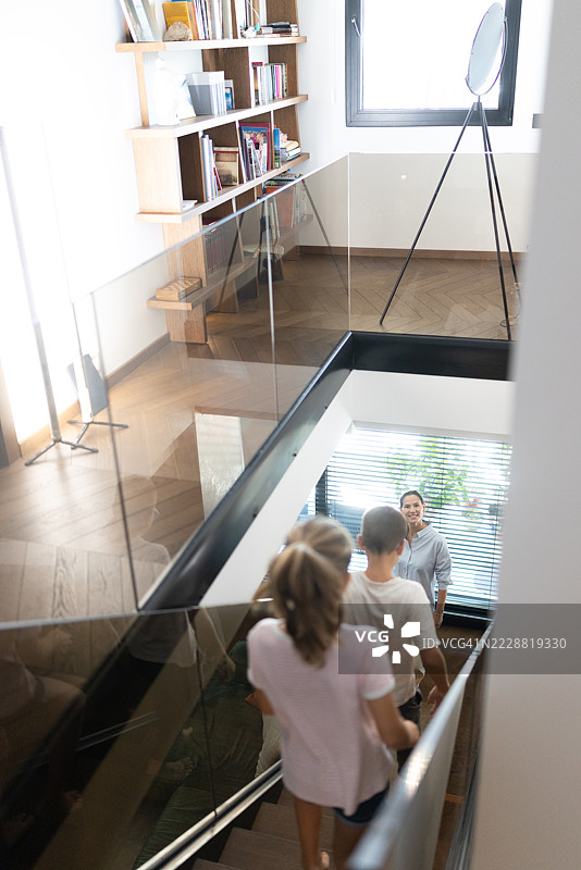 家庭在明亮的家居室内设计中走下现代楼梯图片素材