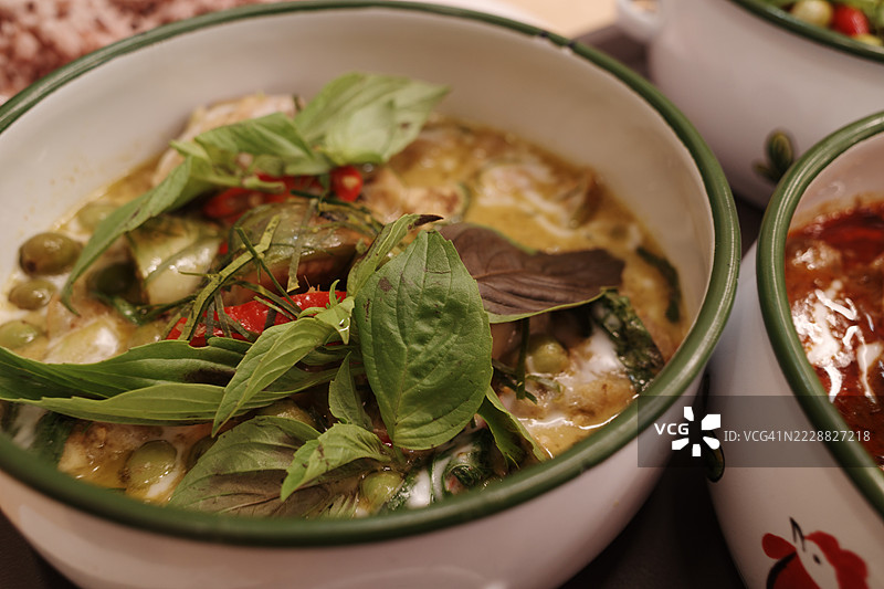 一碗香辣的泰式绿咖喱，配有罗勒和茄子图片素材