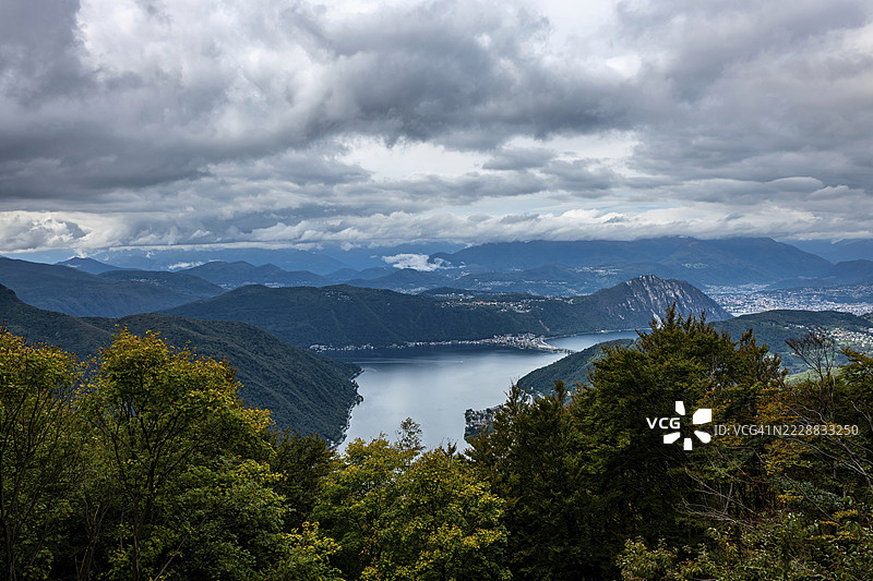 美丽的城市和卢加诺湖及瑞士阿尔卑斯山的航拍视角,秋季的阴天云雾缭绕,位于瑞士提契诺州的卢加诺。图片素材
