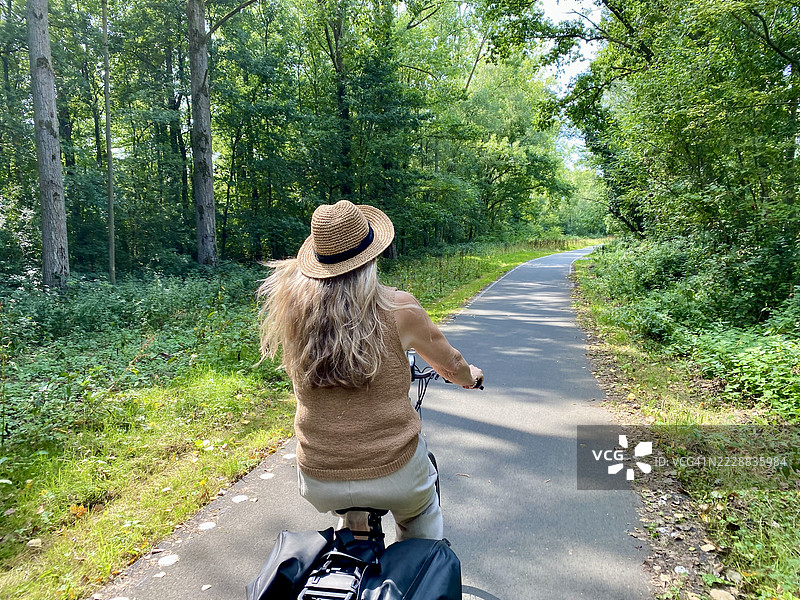年长女性骑电动自行车在乡村旅行。图片素材