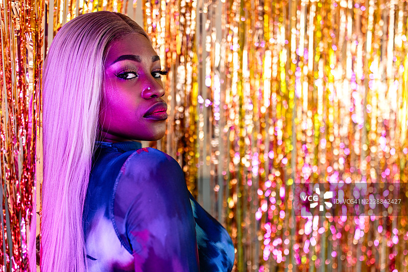 一位迷人的黑人女性在闪亮的金色背景前摆姿势的肖像图片素材