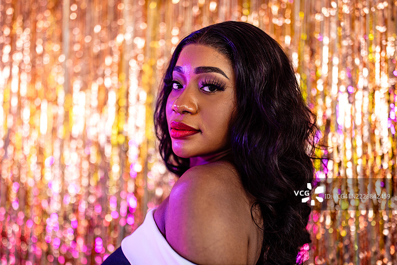 一位迷人的黑人女性在闪亮的金色背景前摆姿势图片素材