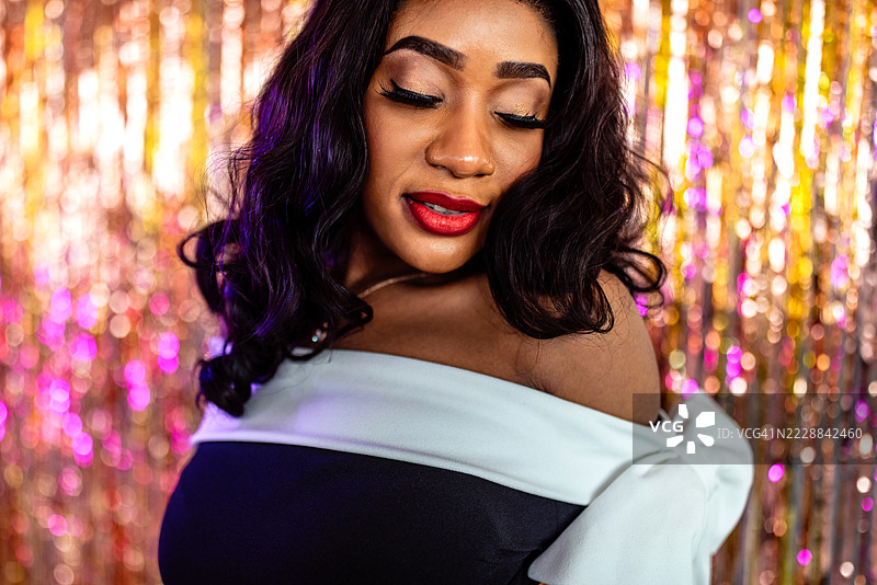 一位迷人的黑人女性在闪亮的金色背景前摆姿势图片素材