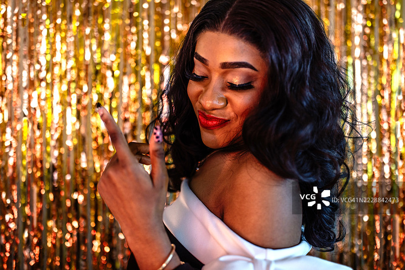 一位迷人的黑人女性在闪亮的金色背景前摆姿势的肖像图片素材