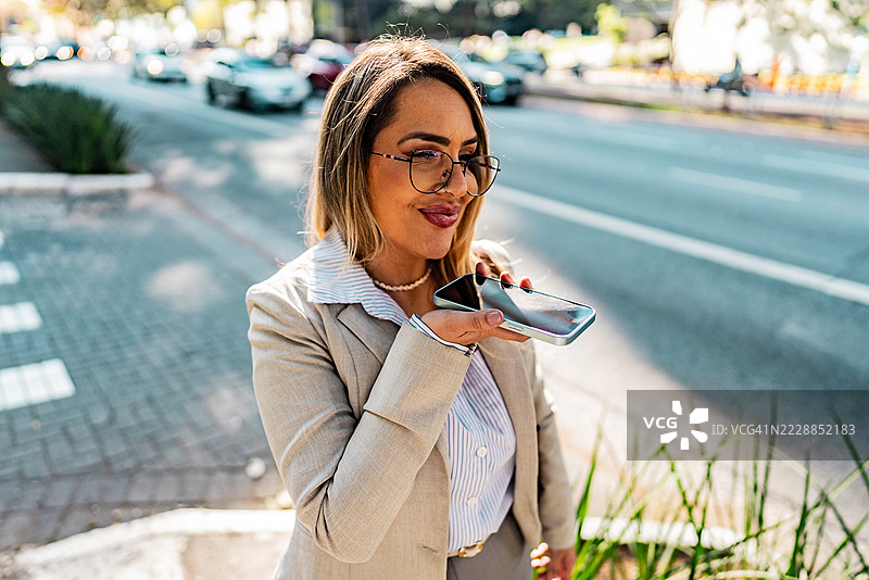 成熟的女商人在街上用手机发送语音信息图片素材