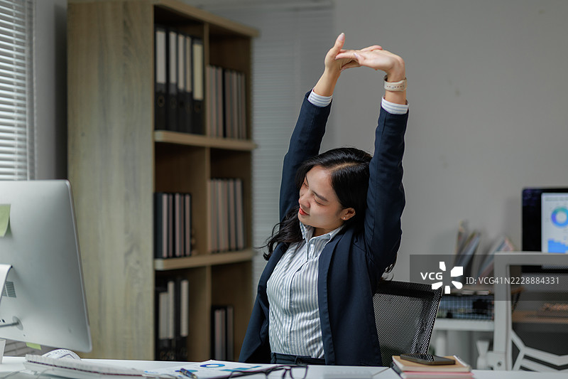 下班后在办公桌前伸展手臂的女商人图片素材