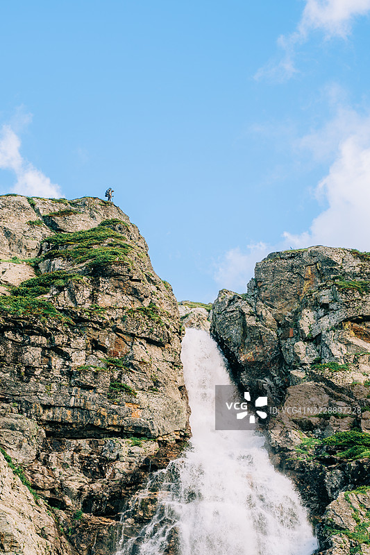 背包客在山顶欣赏瀑布的美景图片素材