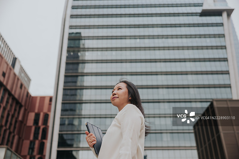 一位穿着智能休闲装的职业女性站在泰国曼谷市中心。图片素材