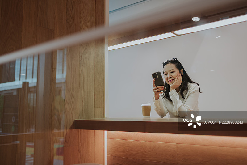 亚洲女性在室内使用手机休息，玩社交媒体。图片素材