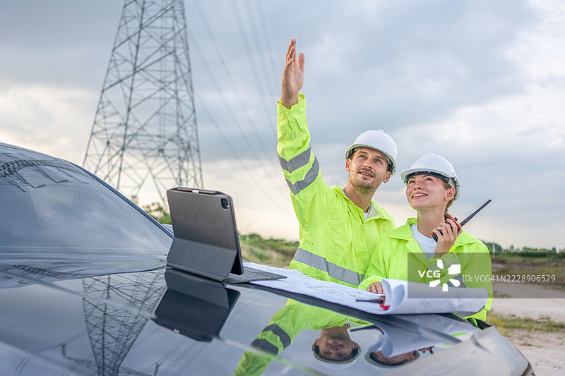 两名男性和一名女性与一位电气工程师在发电厂的半空中握手，讨论电力生产。图片素材