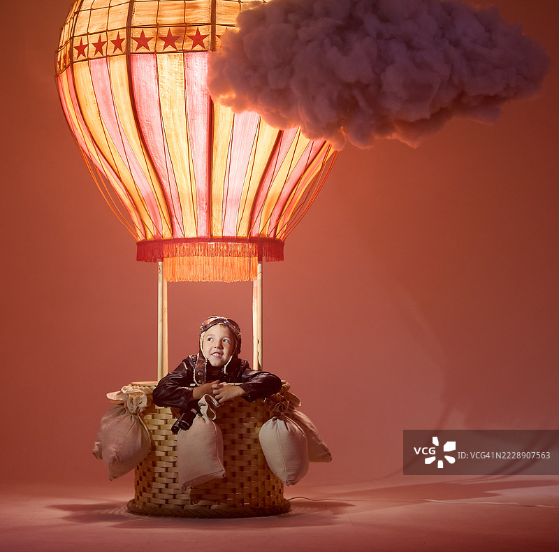 有趣的小男孩气球师坐在热气球里玩飞行游戏图片素材